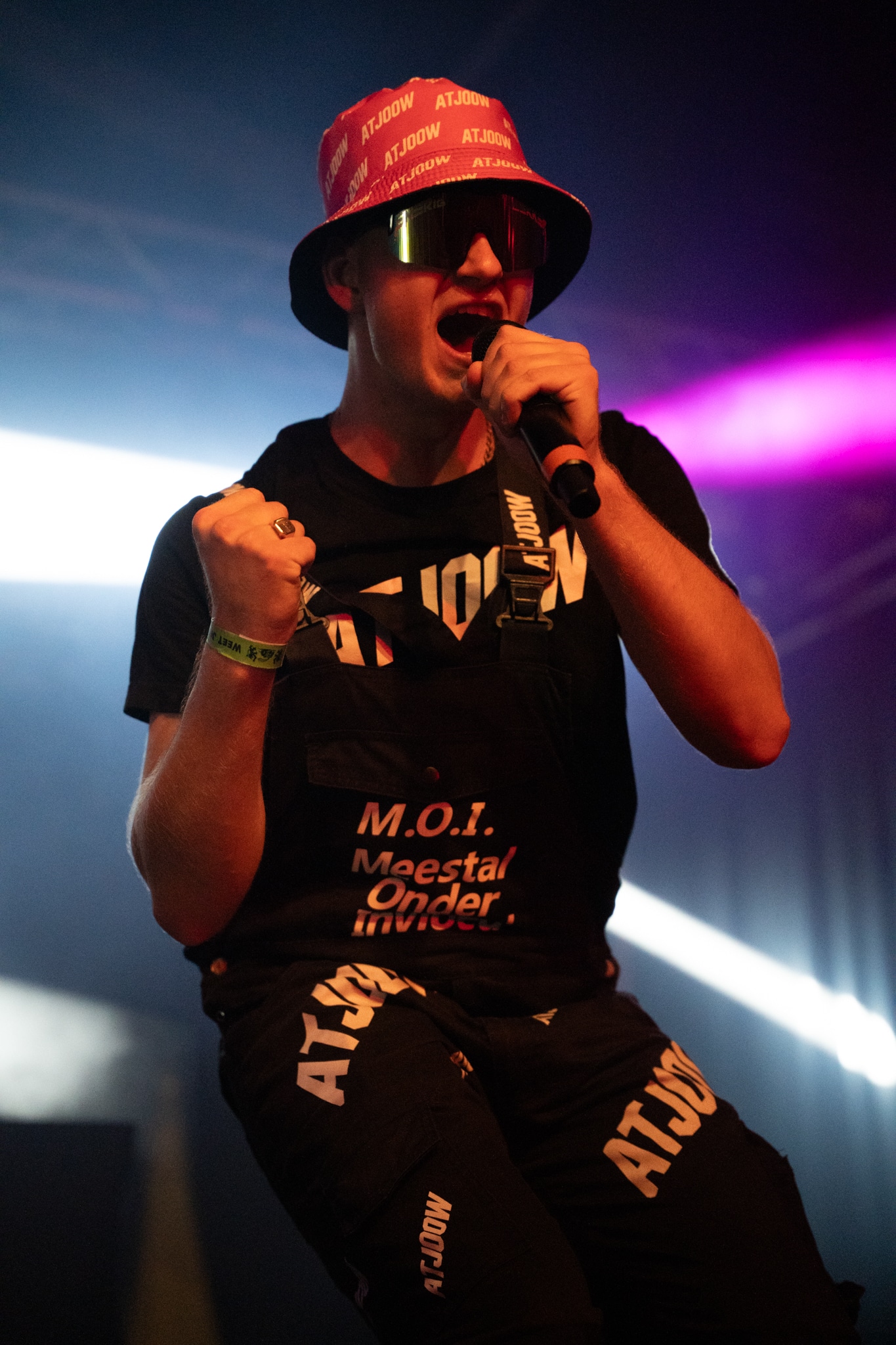 Performer in a red ATJOOW hat singing on stage
