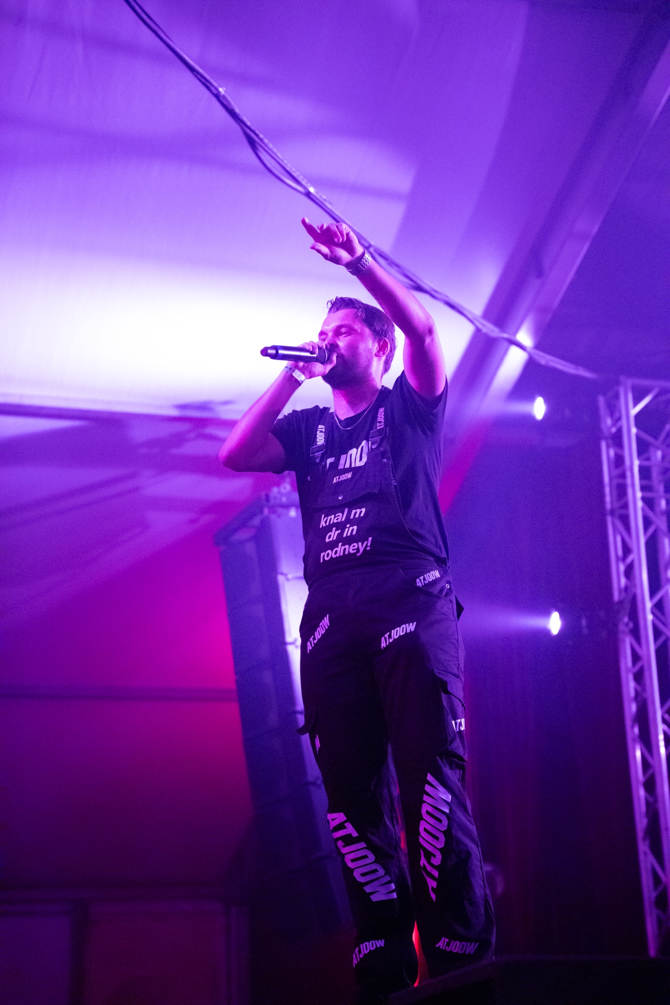 Performer in purple stage light pointing upward
