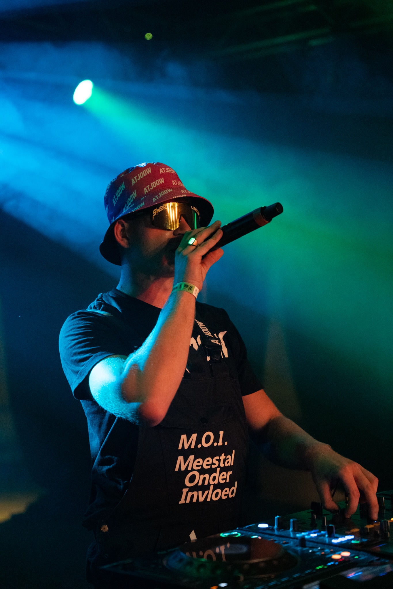 DJ with microphone at the mixer in blue-green light