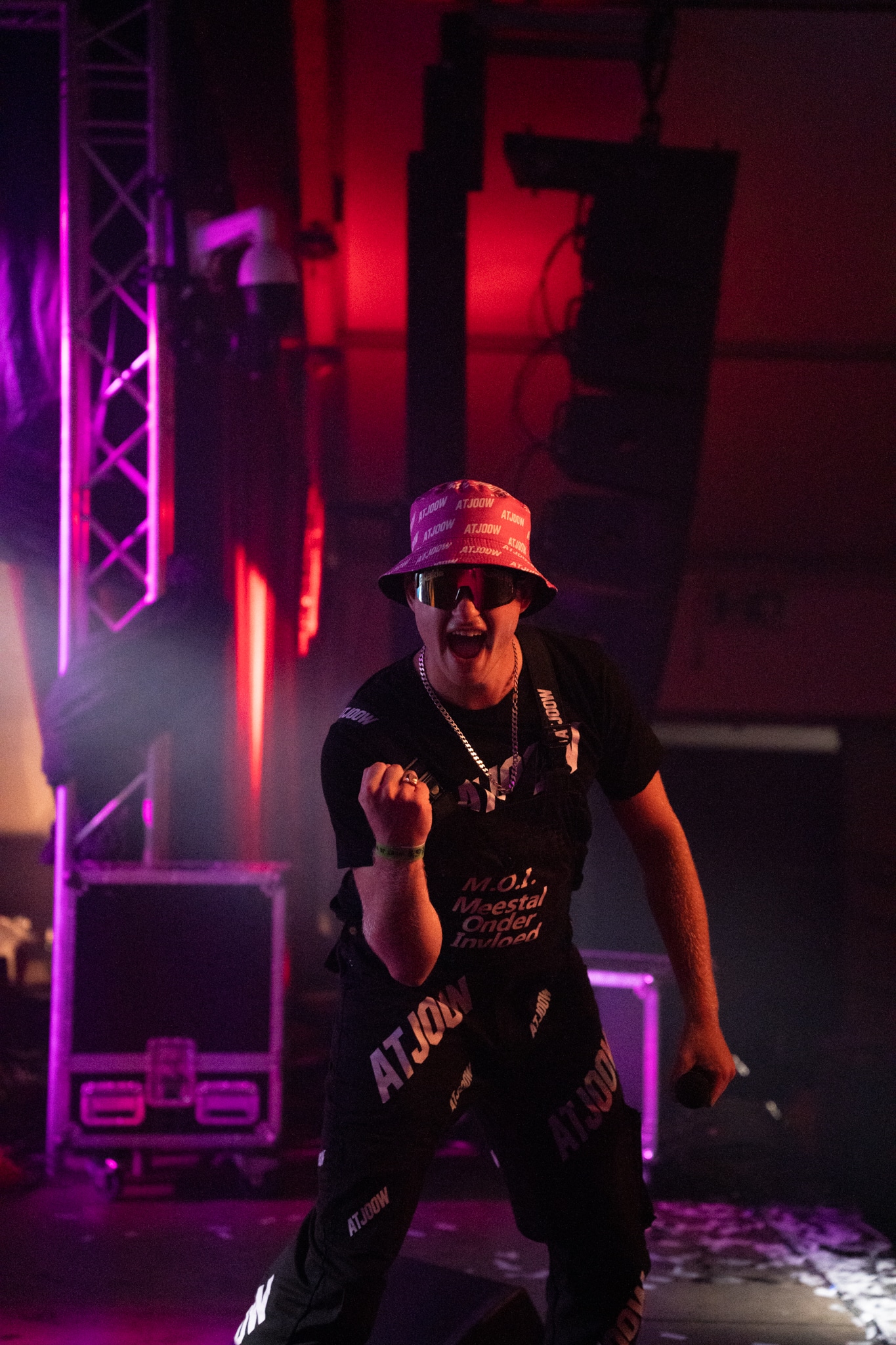 Artist in a pink hat cheering under pink stage light