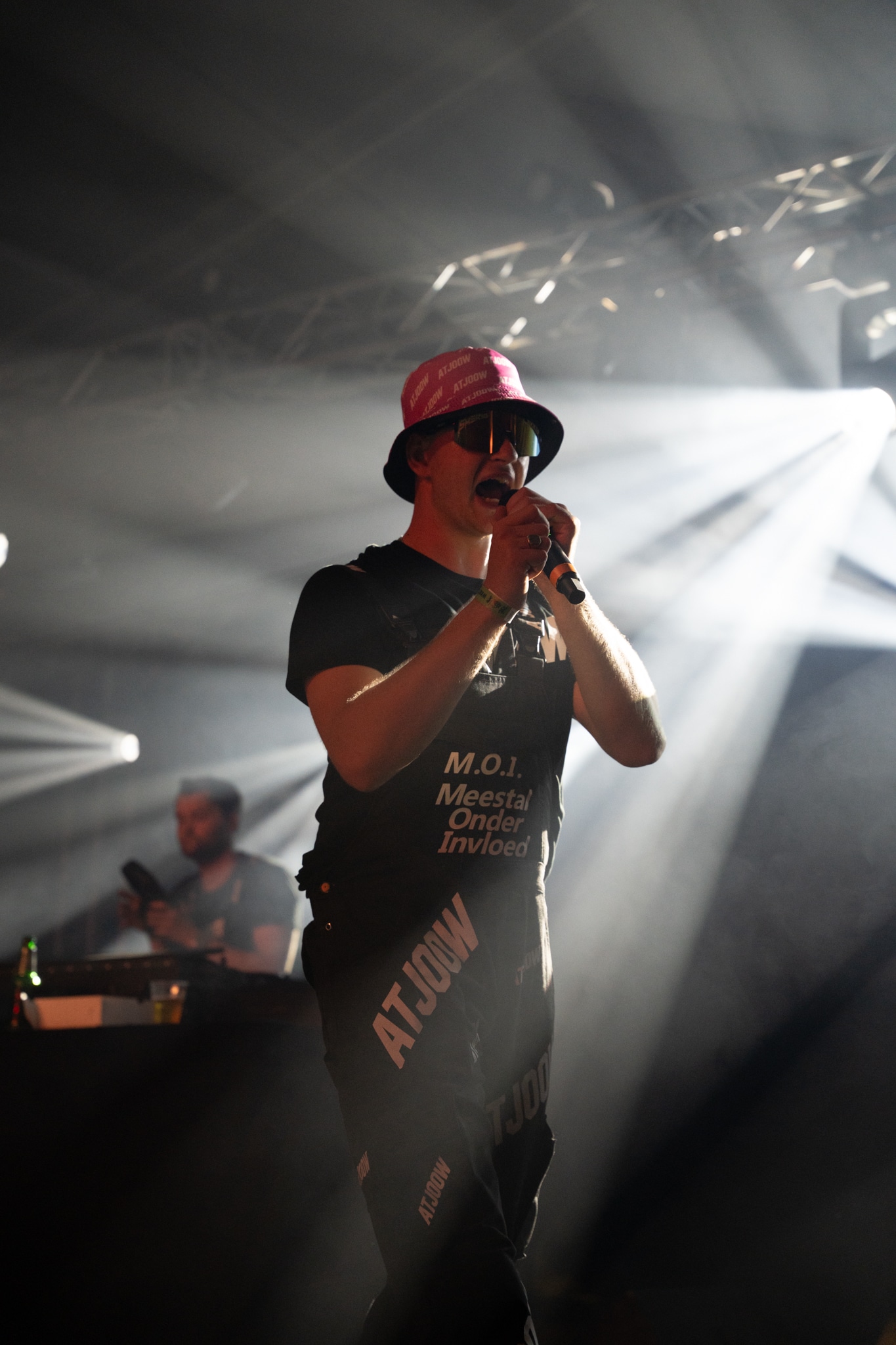 Performer in a pink ATJOOW hat in front of white spotlights