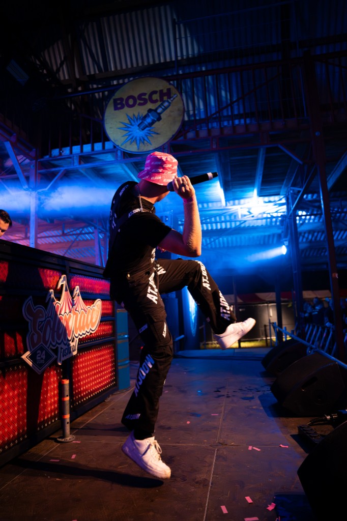 Performer mid-jump on the Solexrace Festival stage in ATJOOW overalls