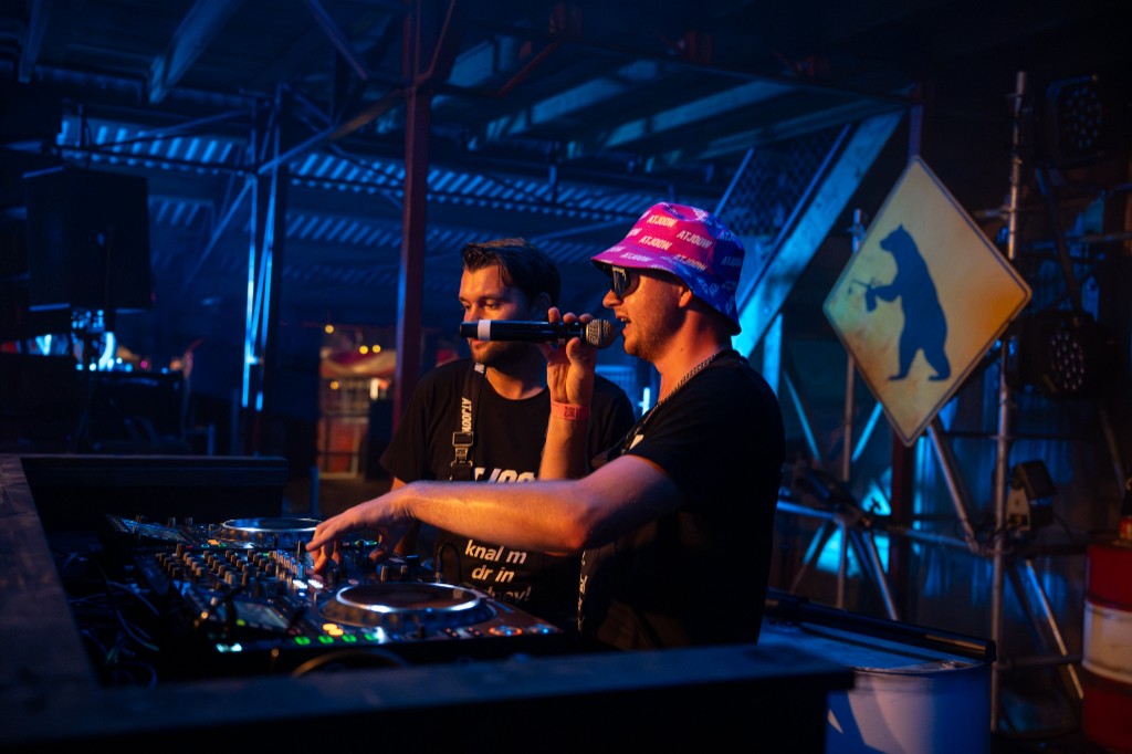 DJ in a pink ATJOOW bucket hat at the mixer under blue and red stage light