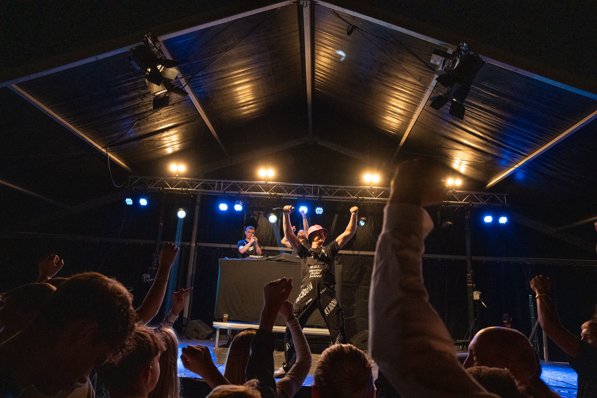Performer with arms raised above the crowd in the party tent