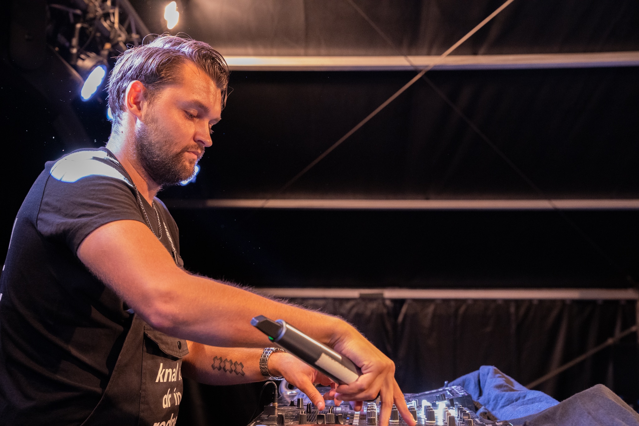 DJ at the mixer holding a microphone in blue stage light