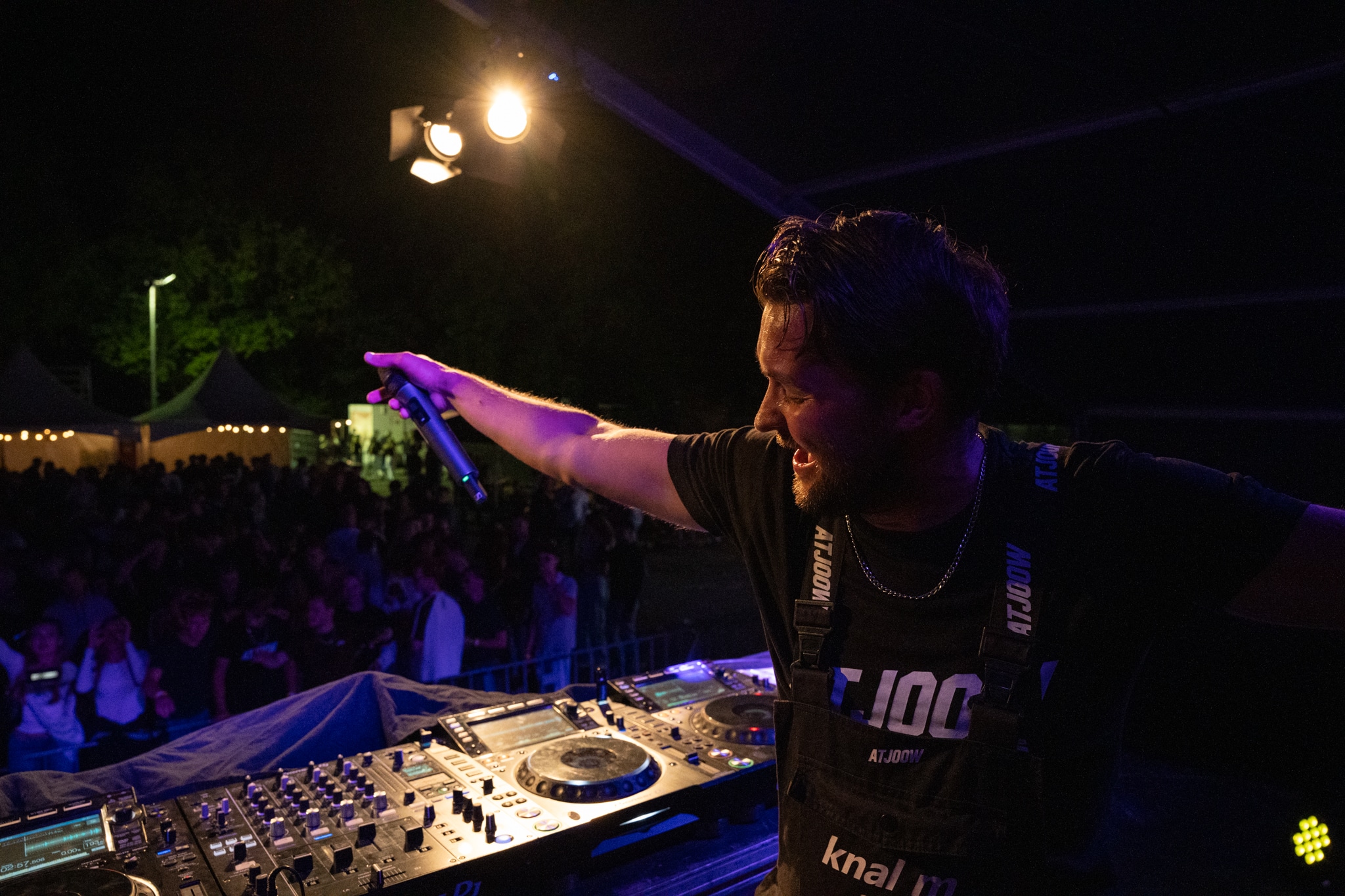 DJ at the Pioneer decks reaching toward the crowd with a microphone